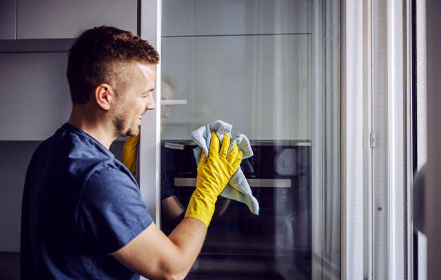Ein Mann mit Handschuhen putzt ein Fenster